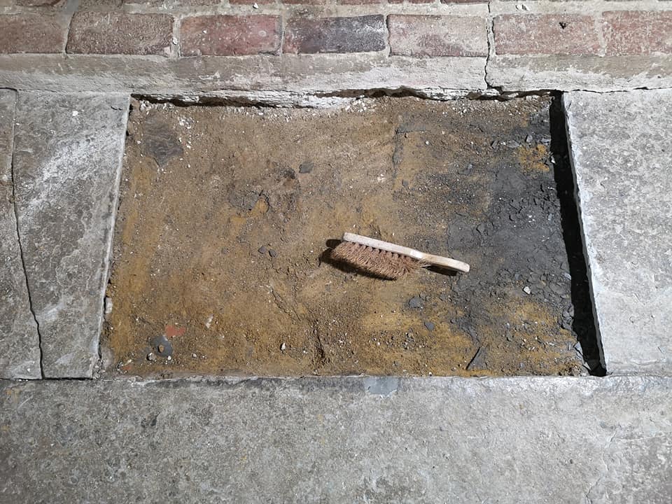Flagstone floor repair preparation showing lifted stone section and cleaning brush